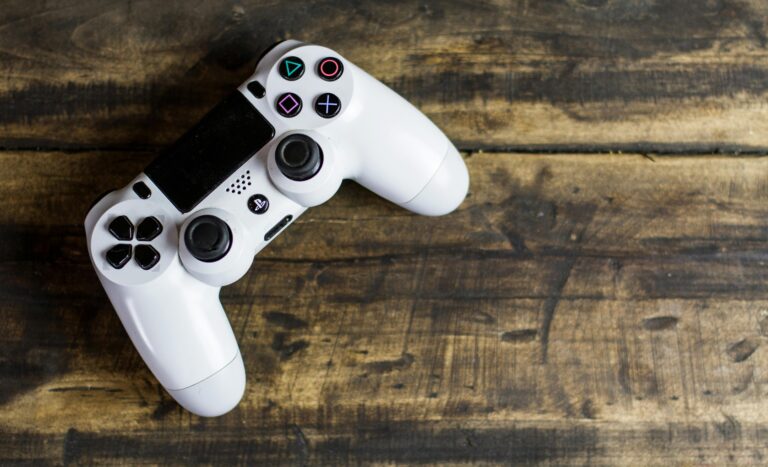 Home White game controller resting on a rustic wooden surface, top view.
